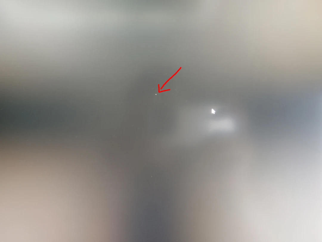 Bright dot defect on a liquid crystal display screen with a grey pattern background.